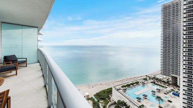 Un hôtel de grande hauteur doté d’un balcon donnant sur une plage et une piscine.
