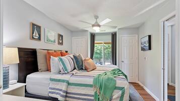 A bedroom with a bed, a ceiling fan, and a window with curtains.