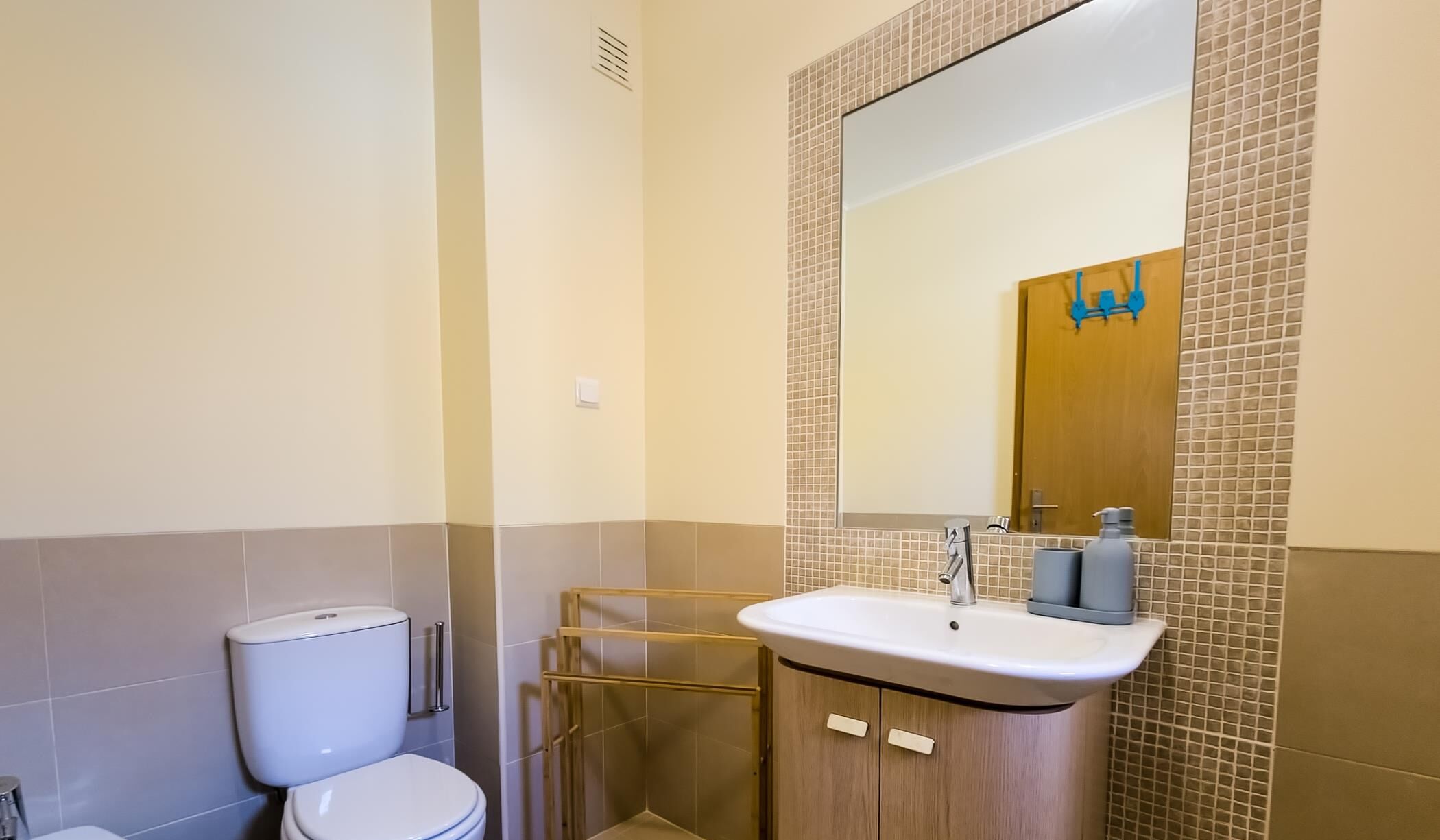 A bathroom with a toilet, a sink, and a mirror.