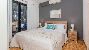 A bedroom with a large bed, a nightstand with a lamp, a wall-mounted mirror, and a sliding glass door leading to an outdoor area. - Amazing apartment in Nin with WiFi (Nin)