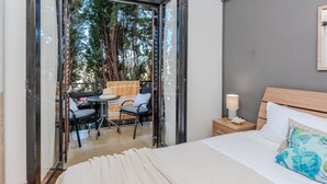 A bedroom with a bed, a nightstand, a lamp, and a view of an outdoor seating area with chairs and a table. - Amazing apartment in Nin with WiFi (Nin)