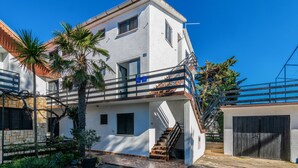 A two-story building with a white exterior, a balcony, and a staircase leading to the upper floor. - Amazing apartment in Nin with WiFi (Nin)
