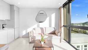 Een moderne woonkamer met een bank, een salontafel en uitzicht op een stadsbeeld door grote ramen.