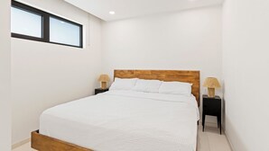 Ein modernes Schlafzimmer mit Holzbettgestell, weißer Bettwäsche und zwei Nachttischlampen.