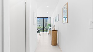 A modern hallway with a wooden column, framed artwork, and a view to a balcony with outdoor seating. - B204 - Amazing 1 Bedroom with terrace (Sint Maarten)