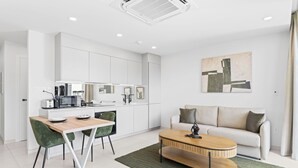 A modern, well-lit living area with a kitchen, a dining table with chairs, a sofa, and a coffee table. - B204 - Amazing 1 Bedroom with terrace (Sint Maarten)