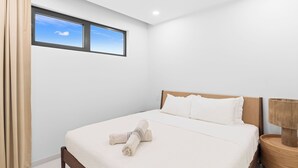 A hotel room with a large bed, a nightstand, a window with a view of the sky, and a curtain. - B204 - Amazing 1 Bedroom with terrace (Sint Maarten)