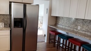 A kitchen with a stainless steel refrigerator, granite countertops, white cabinets, and a coffee maker. - Grand Rapids-Kentwood is close to DT and the airport. (Kentwood)