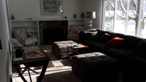 A cozy living room with a fireplace, a sofa, a coffee table, and a patterned armchair. - Grand Rapids-Kentwood is close to DT and the airport. (Kentwood)
