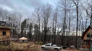 A rural property with a gravel driveway, a parked pickup truck, and a small wooden cabin. - Yurt in Middlebury, Vermont (Middlebury)