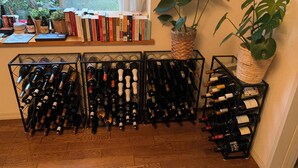 A room with a wine rack filled with bottles, a bookshelf with books, and a window with a view of trees and a fence. - Large 3-bedroom house in Ota-ku suburb with garden. Close to city and airport. (Ota City)