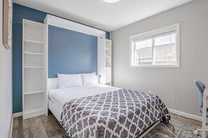 A bedroom with a bed, a white wardrobe, a window, and a blue wall. - Pedal Paradise: Backyard Fun for Bike Lovers (Fruita)