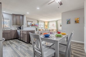 A modern kitchen with wooden cabinets, a dining table set with colorful plates, and a ceiling fan. - Pedal Paradise: Backyard Fun for Bike Lovers (Fruita)