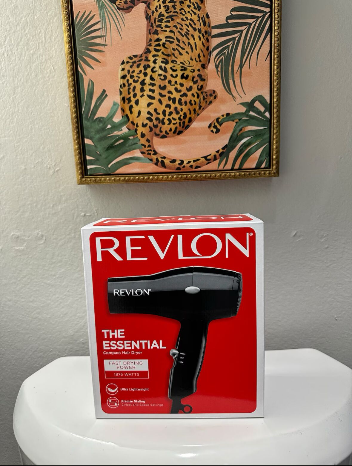A Revlon hair dryer box on a white pedestal.