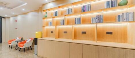 A reception area with a wooden counter, bookshelves, and two orange chairs.