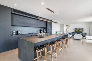 Une cuisine moderne dotée d’un îlot central, de tabourets de bar et d’un coin repas avec un canapé blanc.