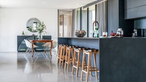 Een moderne keuken met een bar, een eettafel met stoelen en een grote spiegel.