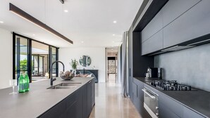 Een moderne keuken met een centraal eiland, ingebouwde apparaten en een groot raam.