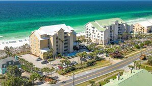 A coastal hotel with multiple buildings, a parking lot, and a beach view. - Charming Destin Home | Yard, Pool & Beach Access (Destin)