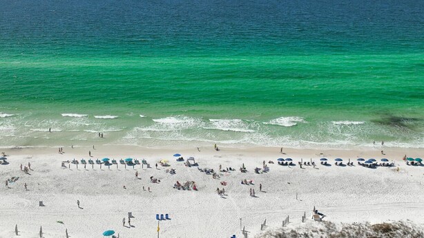 A beach with clear turquoise water, sandy shore, and umbrellas. - Charming Destin Home | Yard, Pool & Beach Access (Destin)