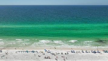 Una playa con agua turquesa cristalina, orilla de arena y sombrillas.