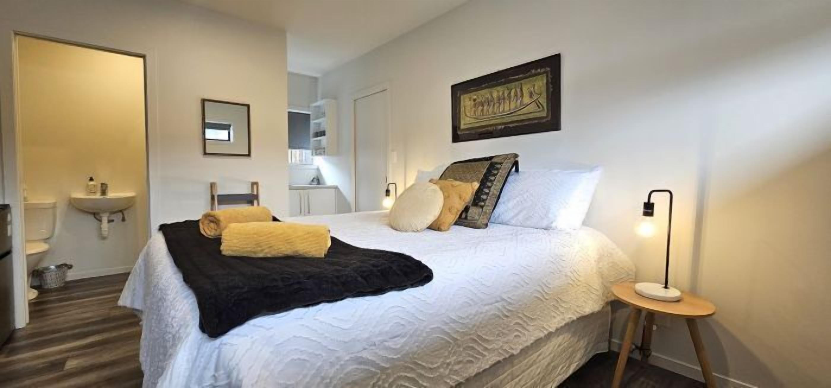 A neatly arranged bedroom with a bed, bedside table, and a nightstand.