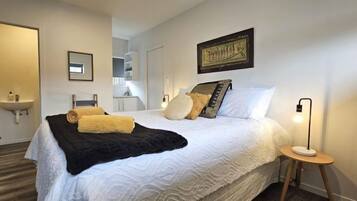 A neatly arranged bedroom with a bed, bedside table, and a nightstand.
