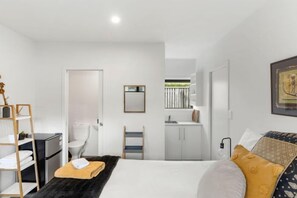 Een moderne hotelkamer met een bed, bureau, kledingkast en een badkamer.