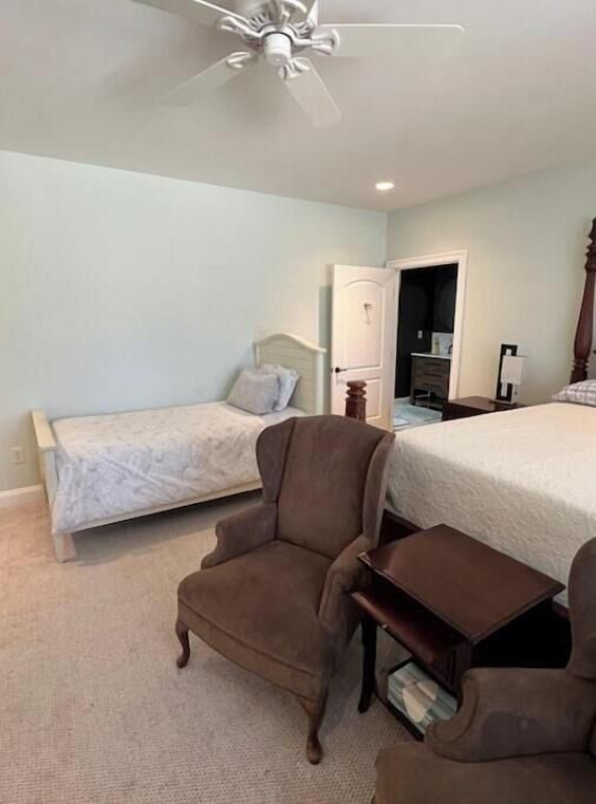 Une chambre avec un lit simple, une chaise, une petite table et une armoire.