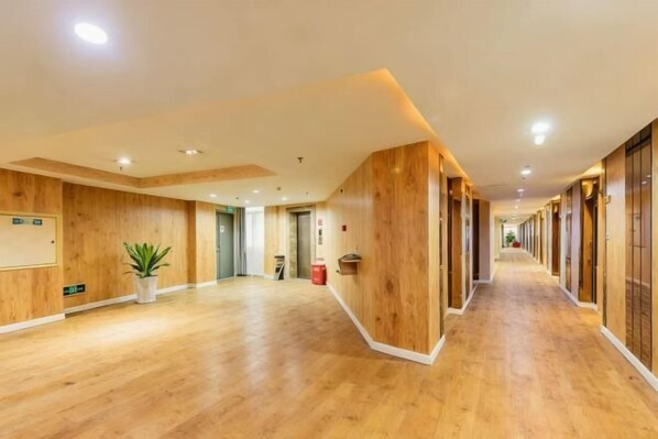 A long, narrow hallway with wooden paneling and a wooden floor. - Quangui Hotel (Shishi)