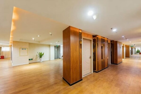 Un amplio vestíbulo de hotel con suelo de madera, una recepción y una puerta que conduce a otra habitación.