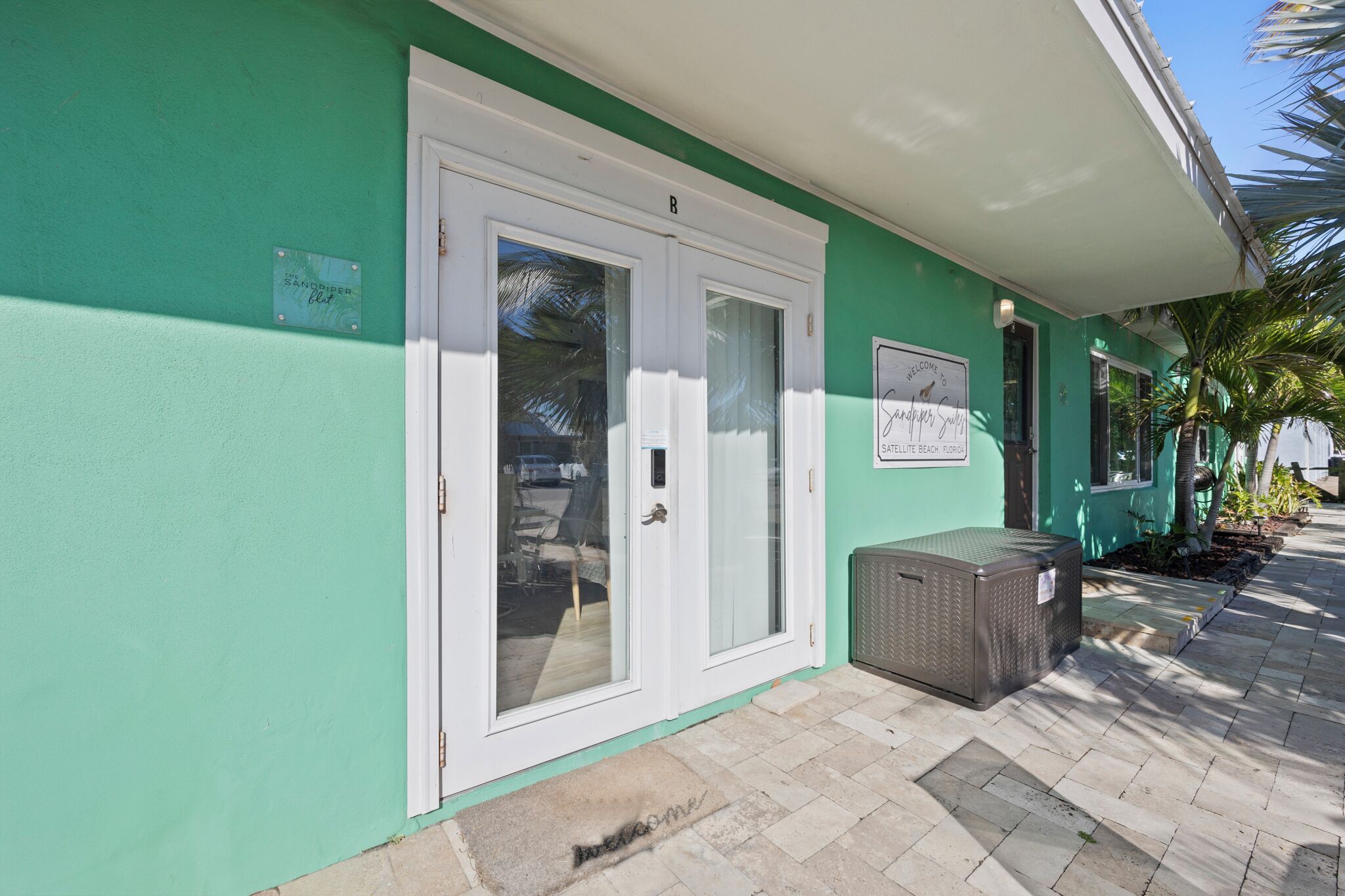Un edificio con fachada verde, una puerta blanca y un letrero que dice "SANDDIPPER CLUB".