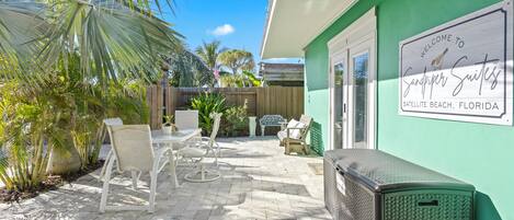 Un patio con mobiliario exterior, una pared verde con un letrero de bienvenida y vistas de los alrededores.
