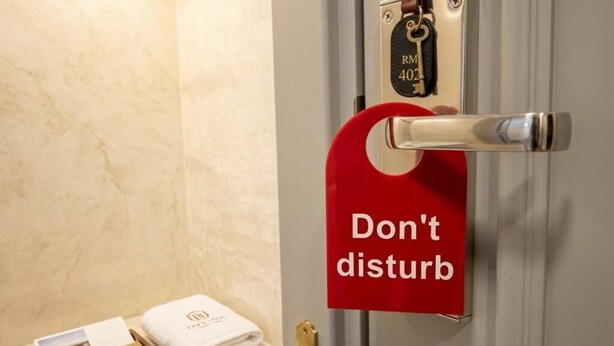 A hotel room door with a 'Don't disturb' sign, a keycard holder, a towel, and a brochure on the counter. - Urbanix Hotel Baku (Baku)