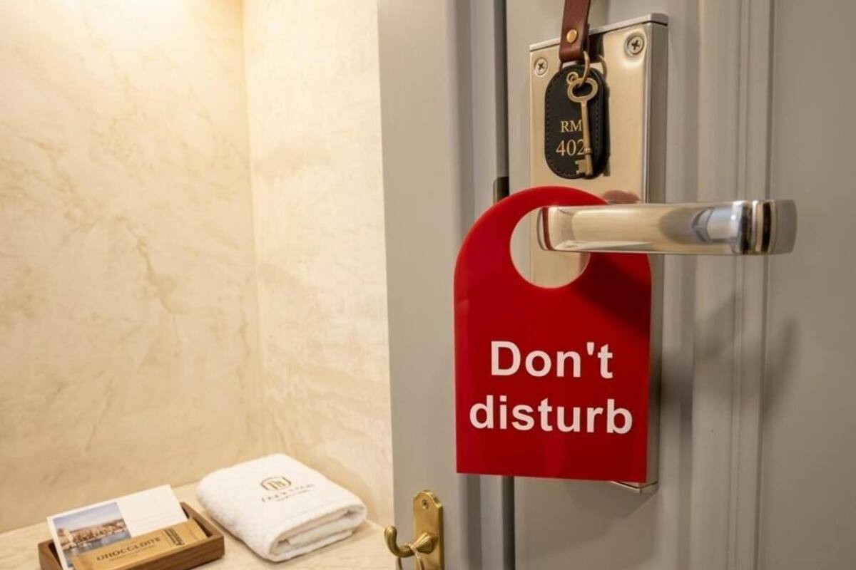 A hotel room door with a 'Don't disturb' sign, a keycard holder, a towel, and a brochure on the counter.