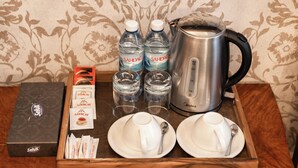 A tray with a coffee maker, water bottles, tea packets, cups, and a box of tea on a wooden surface. - Urbanix Hotel Baku (Baku)