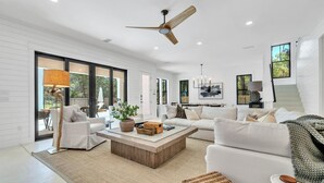 A spacious living room with a large white sofa, a wooden coffee table, and a ceiling fan.