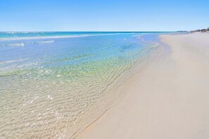 Une plage avec une eau claire et peu profonde et une vaste étendue de sable.