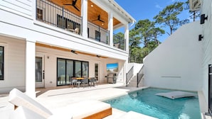 A modern house with a pool, outdoor seating, and a covered patio.