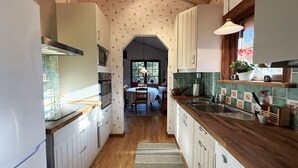 Une cuisine avec des meubles en bois, un four encastré et un coin repas comprenant une table et des chaises.