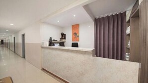 A hotel reception area with a marble counter, a telephone, a computer, and a framed picture on the wall. - Shaoxing Jiajia Business Hotel (Lu Xun Hometown) (Shaoxing)
