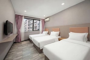 Une chambre d’hôtel avec deux lits, une télévision, une fenêtre avec des rideaux et un appareil de climatisation.