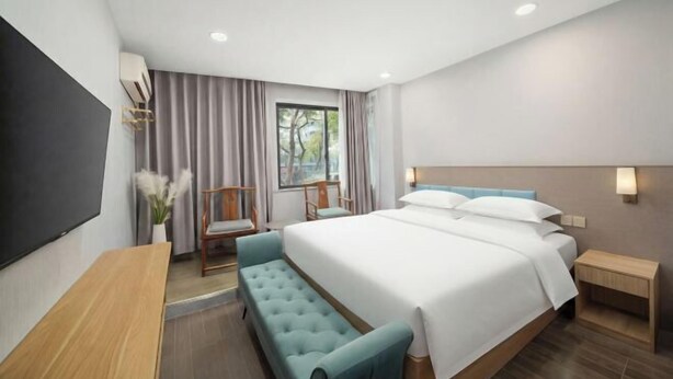 A modern hotel room with a large bed, a desk, a chair, and a TV. - Shaoxing Jiajia Business Hotel (Lu Xun Hometown) (Shaoxing)