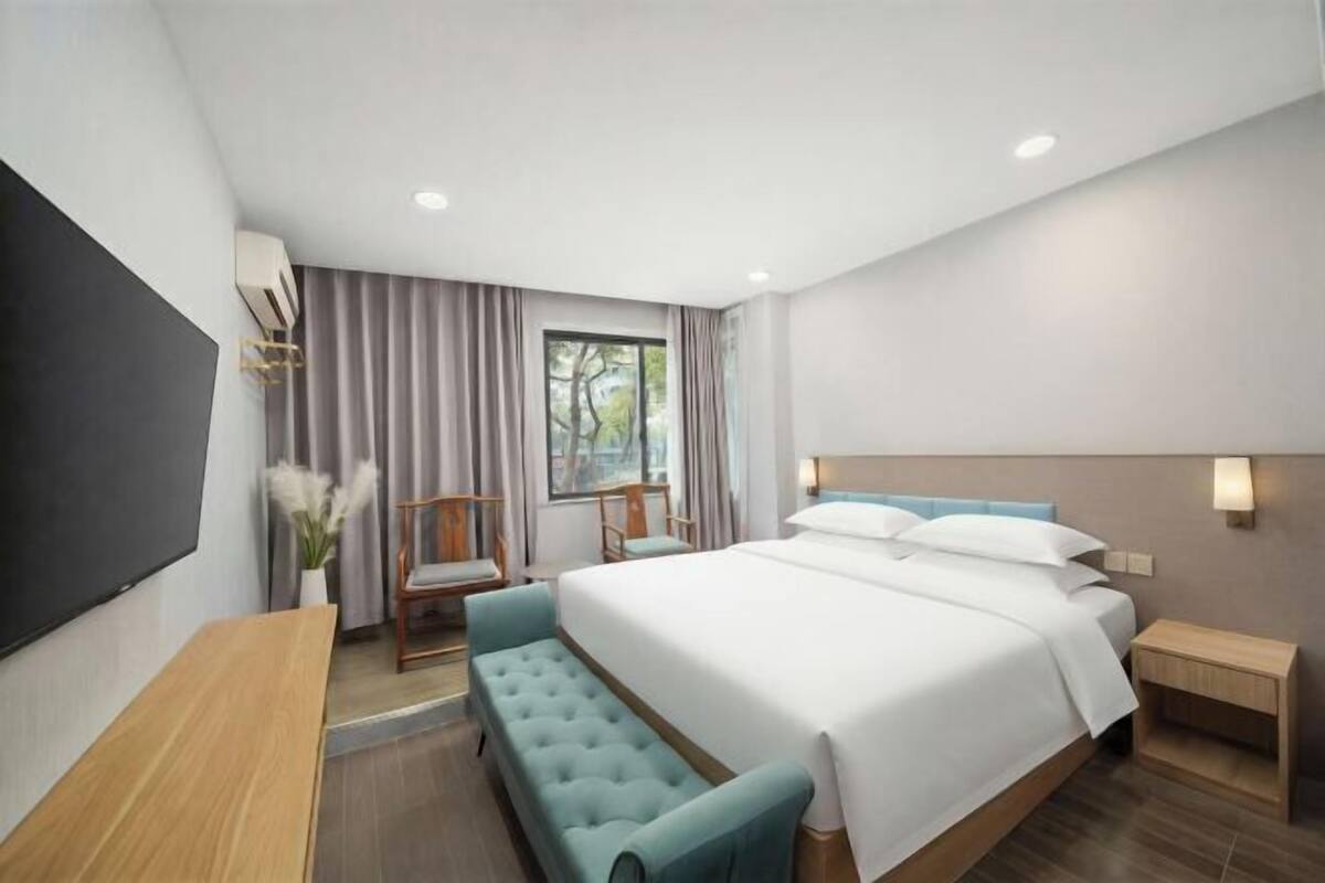 Una habitación de hotel moderna con una cama grande, un escritorio, una silla y un televisor.