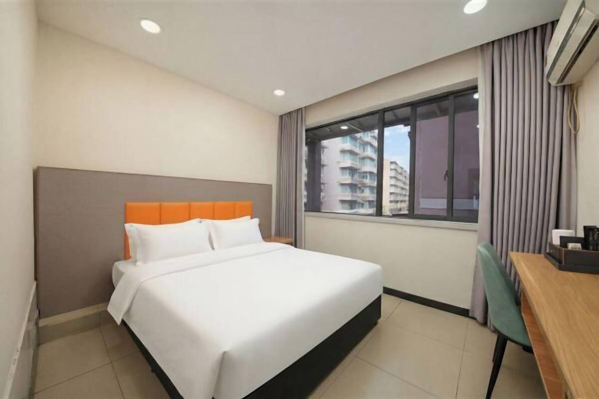 Una habitación de hotel con cama, escritorio y ventana con vistas a edificios.