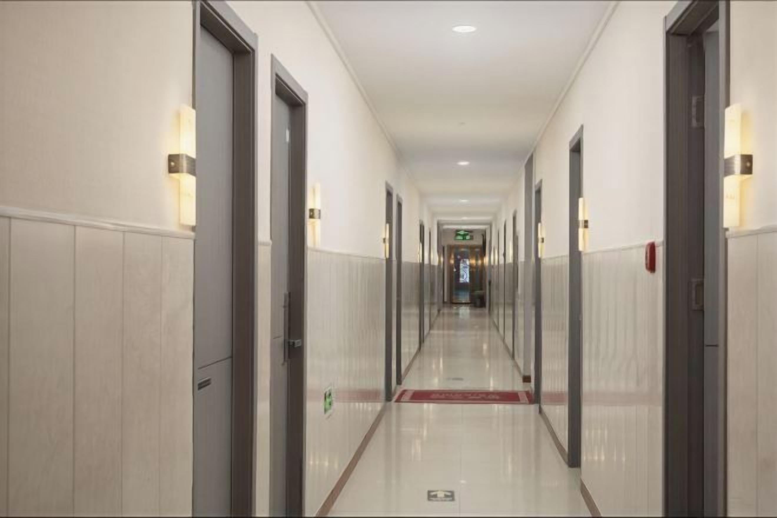 Ein Hotelkorridor mit Türen an beiden Seiten, einem roten Teppich und Notausgangsschildern.