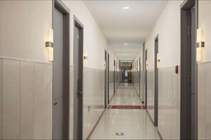 Ein Hotelkorridor mit Türen an beiden Seiten, einem roten Teppich und Notausgangsschildern.