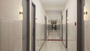 A long, narrow hotel corridor with doors on both sides, a red carpet, and a sign indicating an exit. - Shaoxing Jiajia Business Hotel (Lu Xun Hometown) (Shaoxing)