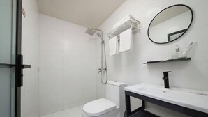 A bathroom with a toilet, shower, sink, mirror, and towel rack. - Shaoxing Jiajia Business Hotel (Lu Xun Hometown) (Shaoxing)