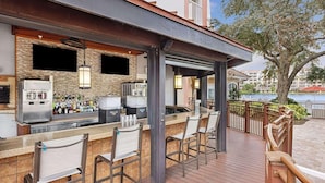 An outdoor bar area with a poolside view, featuring a bar counter, seating, and a view of a body of water. - Escape to Paradise: Your Family Adventure Awaits- Marriott's Grande Vista- 2 Bd (Orlando)